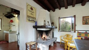 Ein rustikaler Innenraum mit Kamin, Korbmöbeln und Fliesenboden.