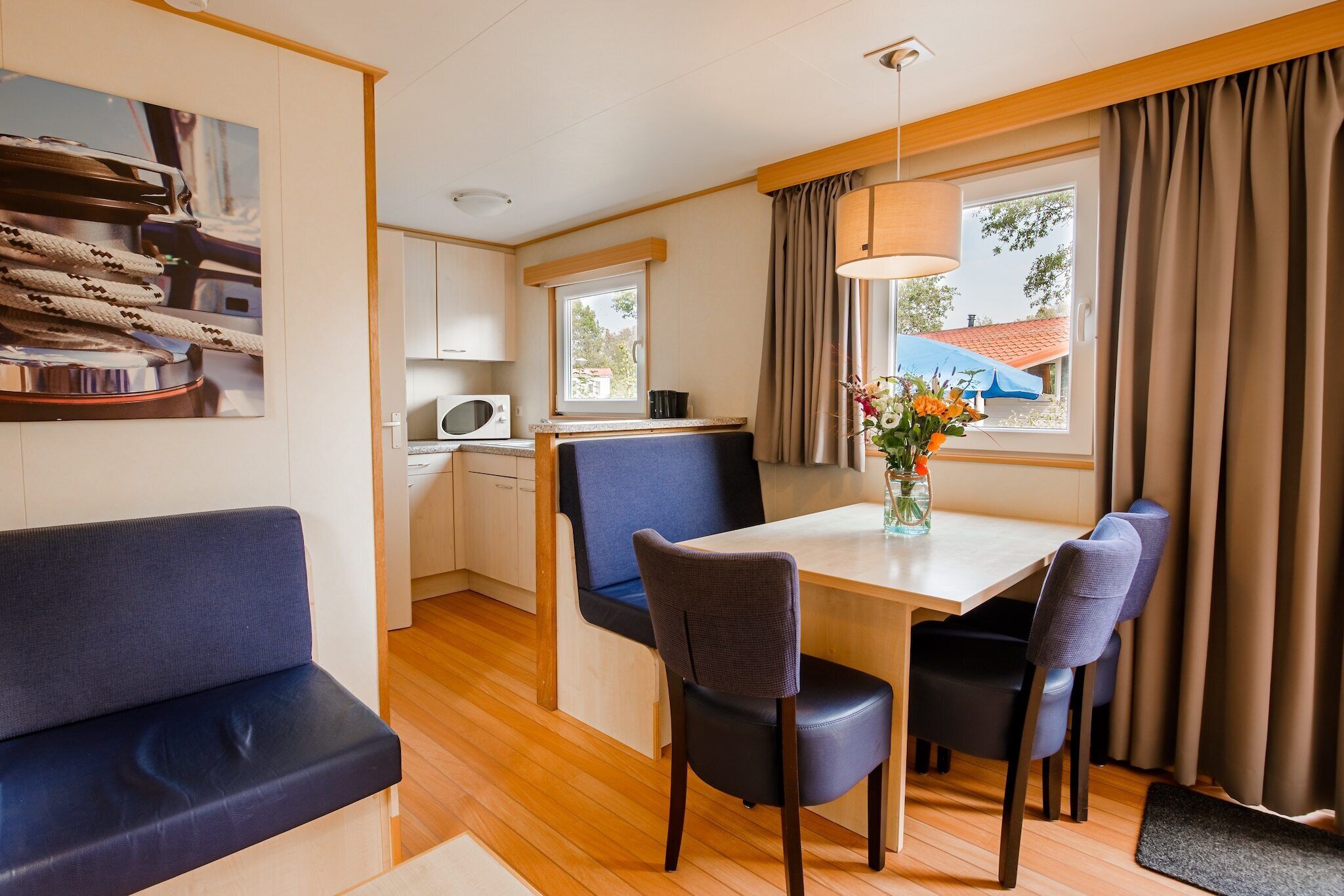 A compact living space with a kitchenette, a dining area with a table and chairs, and a seating area with a sofa.