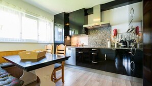 Een moderne keuken met zwarte kastjes, een granieten aanrechtblad en een eethoek met een tafel en stoelen.