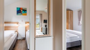 A hotel room with two beds, a radiator, a painting on the wall, and a large mirror. - Covered Terrace Chalet at Leukermeer (Well)