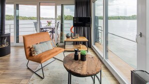 Un salon moderne avec une grande fenêtre, un canapé, une table basse et un téléviseur.
