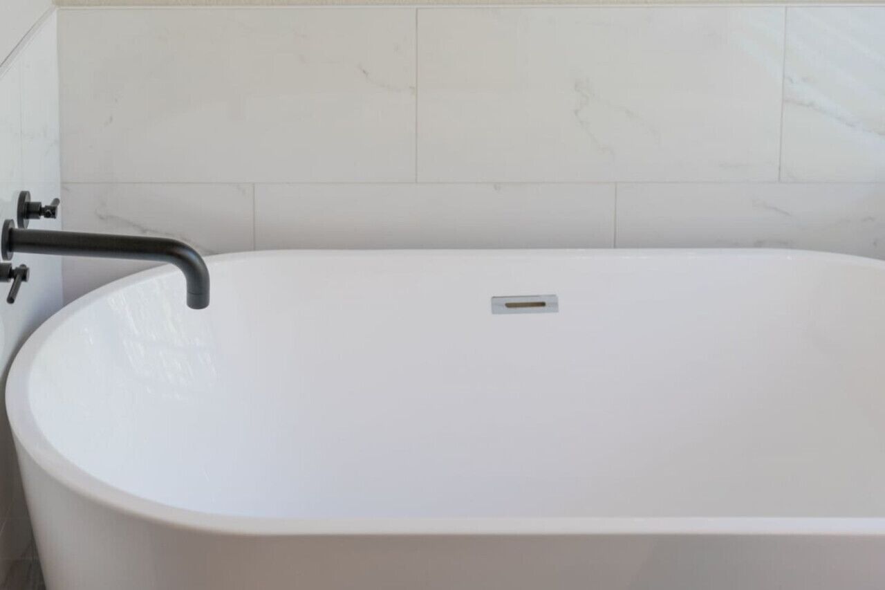 A white bathtub with a black faucet and a small drain.