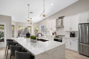 A modern kitchen with a large island, white cabinetry, stainless steel appliances, and pendant lighting. - Heated Pool | Kierland Home Resort | 3bed/2.5bath (Scottsdale)