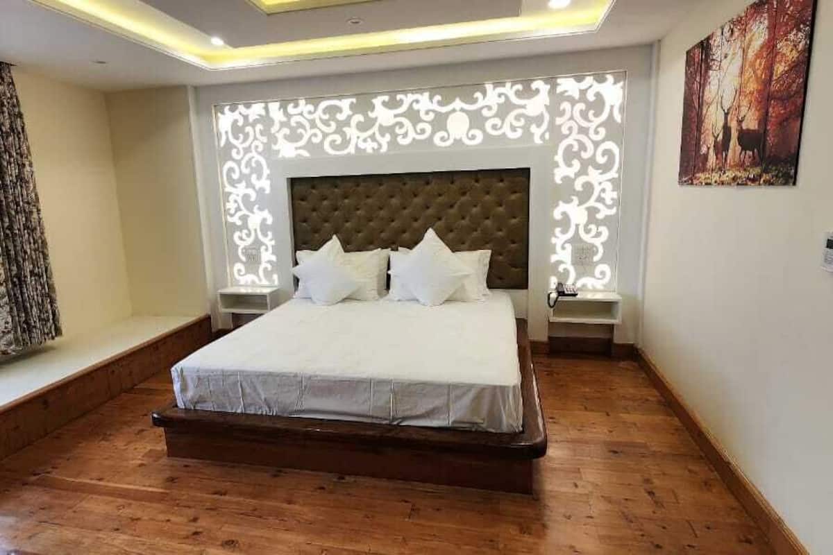 A bedroom with a large bed, a window with curtains, a decorative wall panel, and a painting.