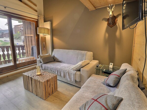 A cozy living room with a sofa, a coffee table, and a mounted TV.