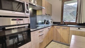 Una cocina moderna con electrodomésticos de acero inoxidable, armarios de madera y un ventanal con vistas a la montaña.