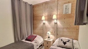 Un dormitorio con dos camas individuales, cabeceros de madera, dos lámparas de noche y un cuadro en la pared.