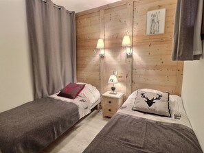 Quarto com duas camas de solteiro, cabeceira de madeira, duas luminárias de apoio e um quadro na parede.