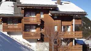 Una cabaña de madera con varios balcones, ubicada en una ladera nevada.