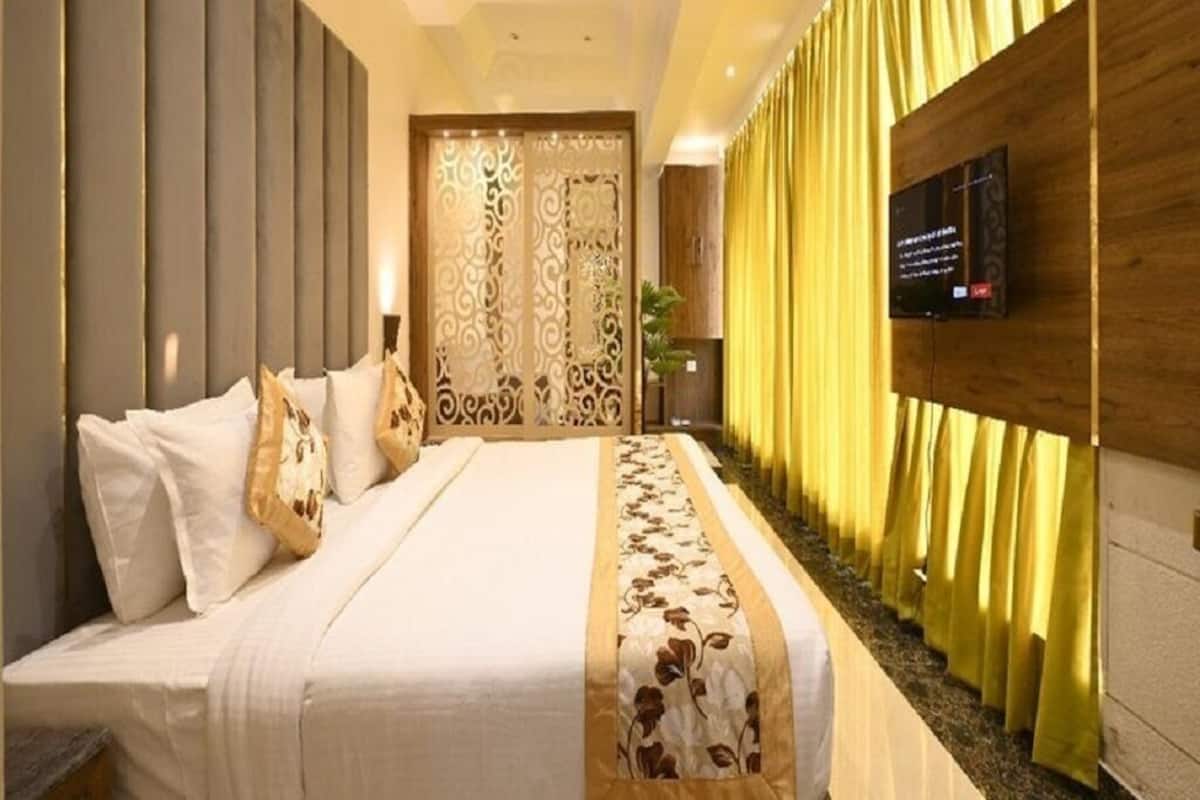 A modern hotel room with a large bed, a TV mounted on the wall, and a decorative partition.