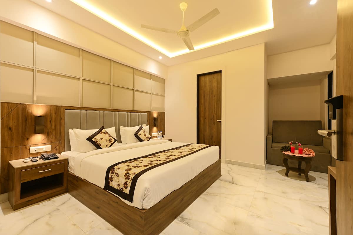 A modern bedroom with a large bed, bedside tables, a ceiling fan, and a small table with drinks.
