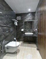 A modern bathroom with a glass-enclosed shower, a white toilet, a sink, and a mirror.