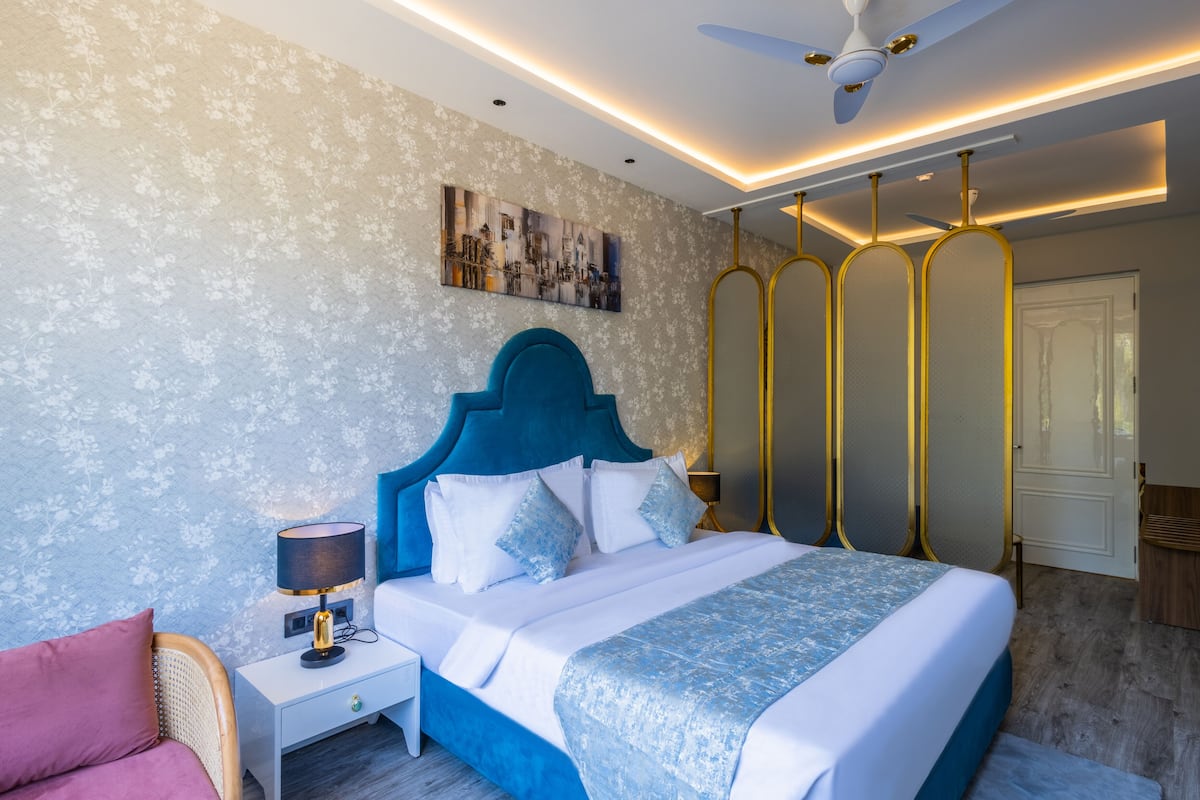 Quarto com cama, mesa de cabeceira, abajur e ventilador de teto.