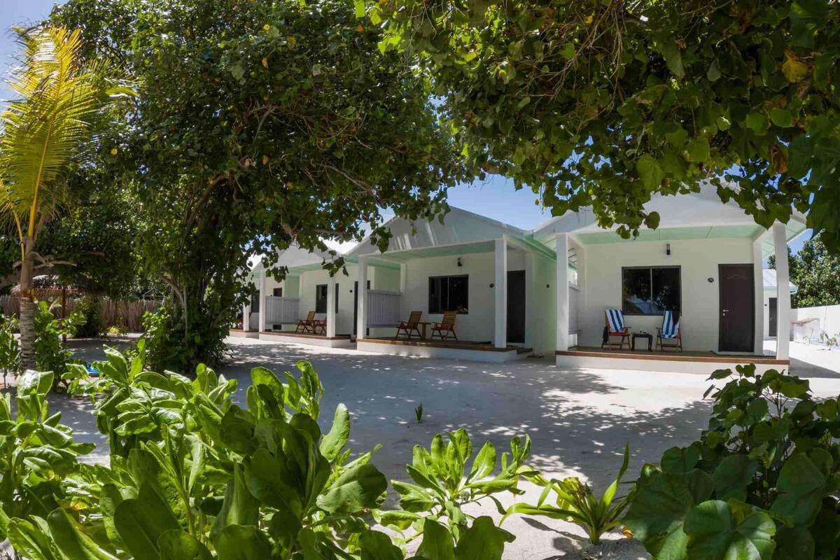 Ein Resort mit mehreren weißen Gebäuden, Sitzbereichen im Freien und üppigem Grün.