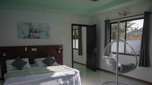 Une chambre à coucher avec un lit, un fauteuil suspendu et un tableau au mur.