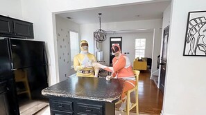 A modern kitchen with a black refrigerator, a dining table, and a chandelier. - Sweet Stay Near Savannah | 3BR Home (Pooler)