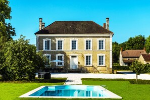 A large two-story house with a swimming pool in front.