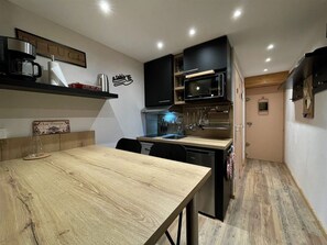 Cozinha compacta com uma mesa de madeira, micro-ondas e máquina de lavar louça.