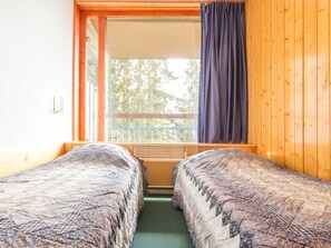 Ein Zimmer mit zwei Betten, einem Fenster mit Blick auf Bäume und Holzwänden.