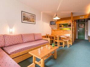 A cozy room with a sofa, a wooden table, and a kitchen area.