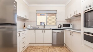 Et moderne køkken med hvide skabe, rustfrie stål hvidevarer og et flisebeklædt backsplash.