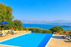 Une piscine avec vue sur la mer et les montagnes lointaines.