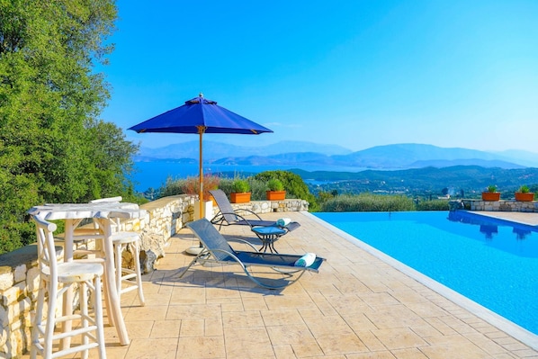 Relax by the pool with a mountain view, surrounded by lush greenery and a patio.