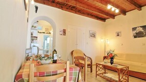 A cozy living room with a wooden ceiling, a dining area with a table and chairs, and a sofa. - Dina Beach Front Apartment (Corfu)