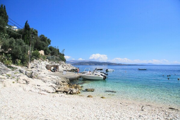 Experience the tranquility of a serene coastal setting with a pebble beach and scenic views of the calm waters.