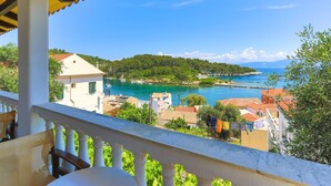 A balcony with a view of a coastal town, including buildings and a body of water. - Faros Tessera in Gaios (Paxos)