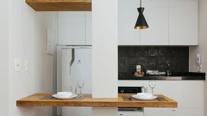 Eine moderne Küche mit weißen Schränken, einer schwarzen Arbeitsplatte und einem Holztisch mit roten Hocker.