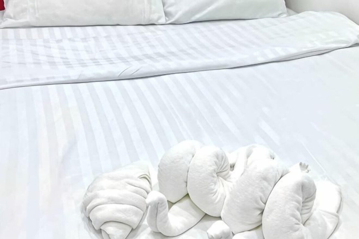 A neatly made bed with white bedding and a white pillow.