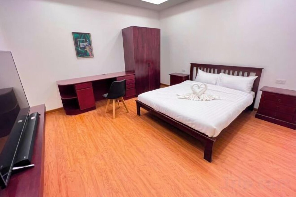 A bedroom with a bed, a desk, and a wardrobe.