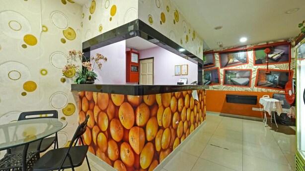 A reception area with a wall decorated with oranges, a glass table with chairs, and a counter with a red and orange design. - Orange Hotel Kuala Pilah (Kuala Pilah)