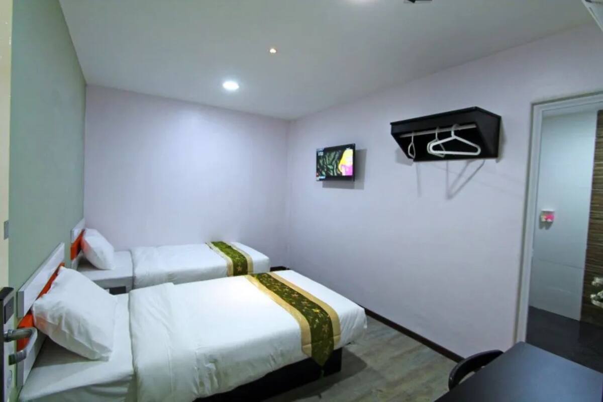 Ett hotellrum med två sängar, en TV, en klädställning och ett skrivbord.