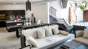 Una sala de estar moderna con un sofá, una mesa de comedor y una cocina al fondo.