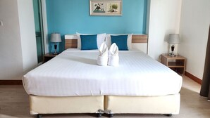 A hotel room with a large bed, two nightstands, a blue accent wall, and a framed picture above the bed. - By Dee @Jomtien (Pattaya)
