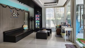A modern hotel lobby with a seating area, a refrigerator, and a large window. - By Dee @Jomtien (Pattaya)