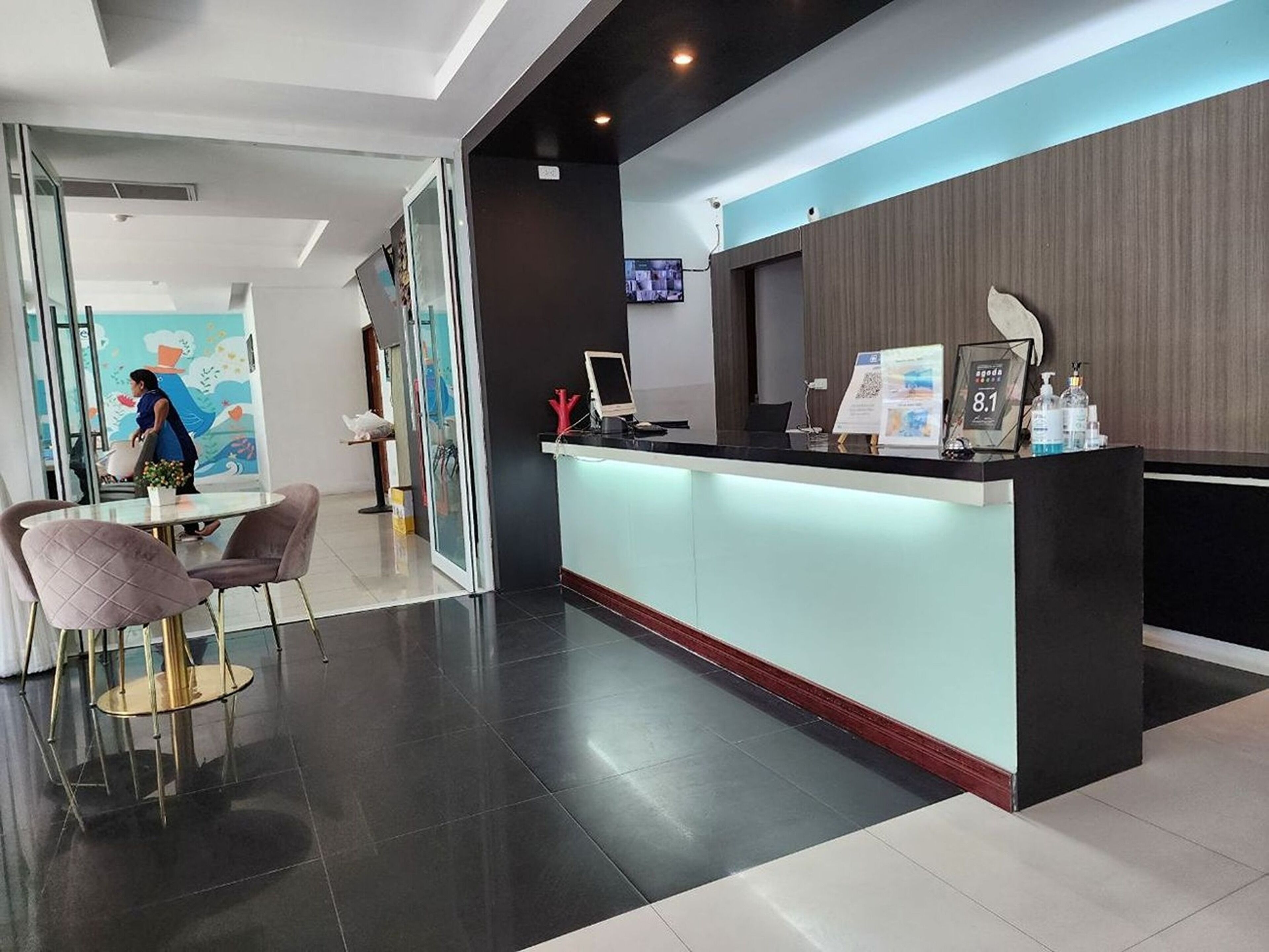 A modern reception area with a glass partition, a reception desk, and a seating area with chairs.