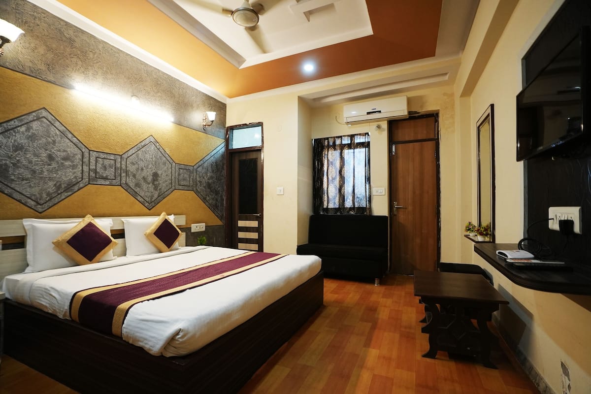 Une chambre d’hôtel avec un grand lit, un bureau, une chaise et un ventilateur de plafond.