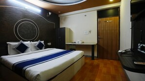 Una habitación de hotel con cama, escritorio, armario y puerta.
