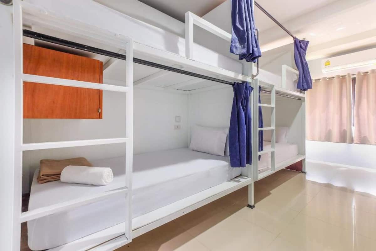 Een kamer met stapelbedden, houten kasten en een douchehoek.