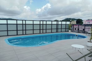 A rooftop swimming pool with a view of the city skyline and mountains in the background. - The Little Nest Phuket (Phuket)