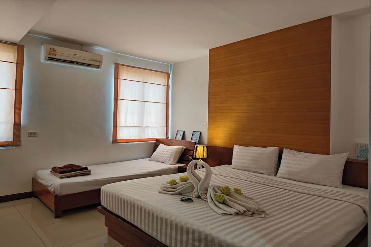 Hotelkamer met twee bedden, een airconditioner, een raam met zonwering en een wand van hout.