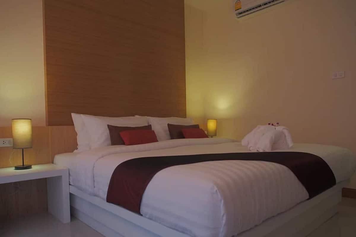 Een moderne hotelkamer met een groot bed, nachtlampjes en een houten hoofdeinde.