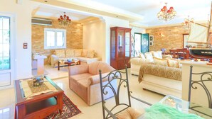 A spacious living room with a high ceiling, a large wooden cabinet, and a dining area with a ship-themed table. - Eleonas in Kato Korakiana (Corfu)