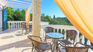 A covered outdoor patio with wicker furniture and a view of the landscape. - Eleonas in Kato Korakiana (Corfu)