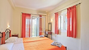 Ein Hotelzimmer mit zwei Betten, einem Badezimmer inklusive Spiegel und einem Fenster mit Vorhängen.