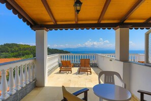 A balcony with two wooden chairs and a small table, overlooking a scenic view of the sea and mountains. - Faros Tria in Gaios With 1 Bedrooms and 1 Bathrooms (Paxos)