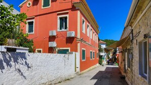 A narrow street with a red building on the left and a stone building on the right. - Faros Octo in Gaios With 1 Bedrooms and 1 Bathrooms (Paxos)